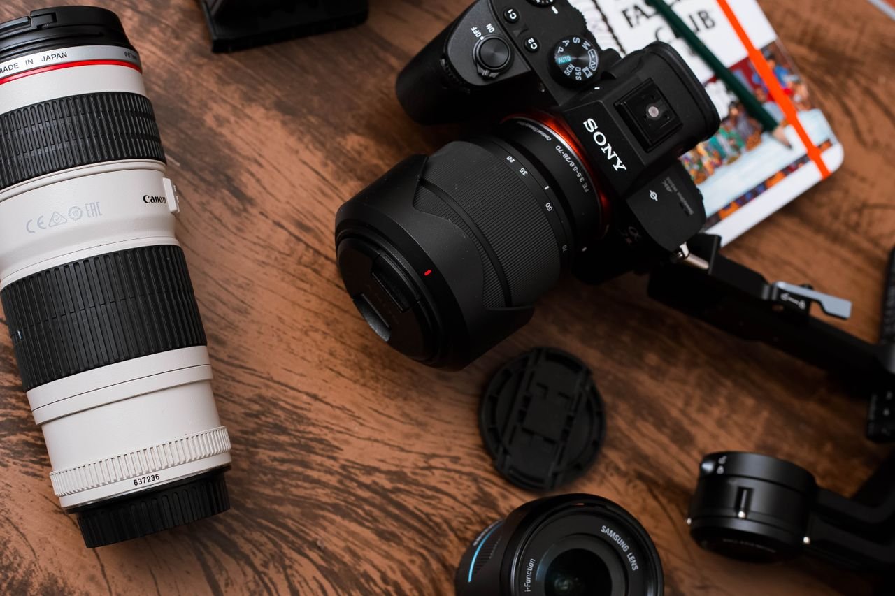 Close-up of various camera lenses and equipment on a wooden table.